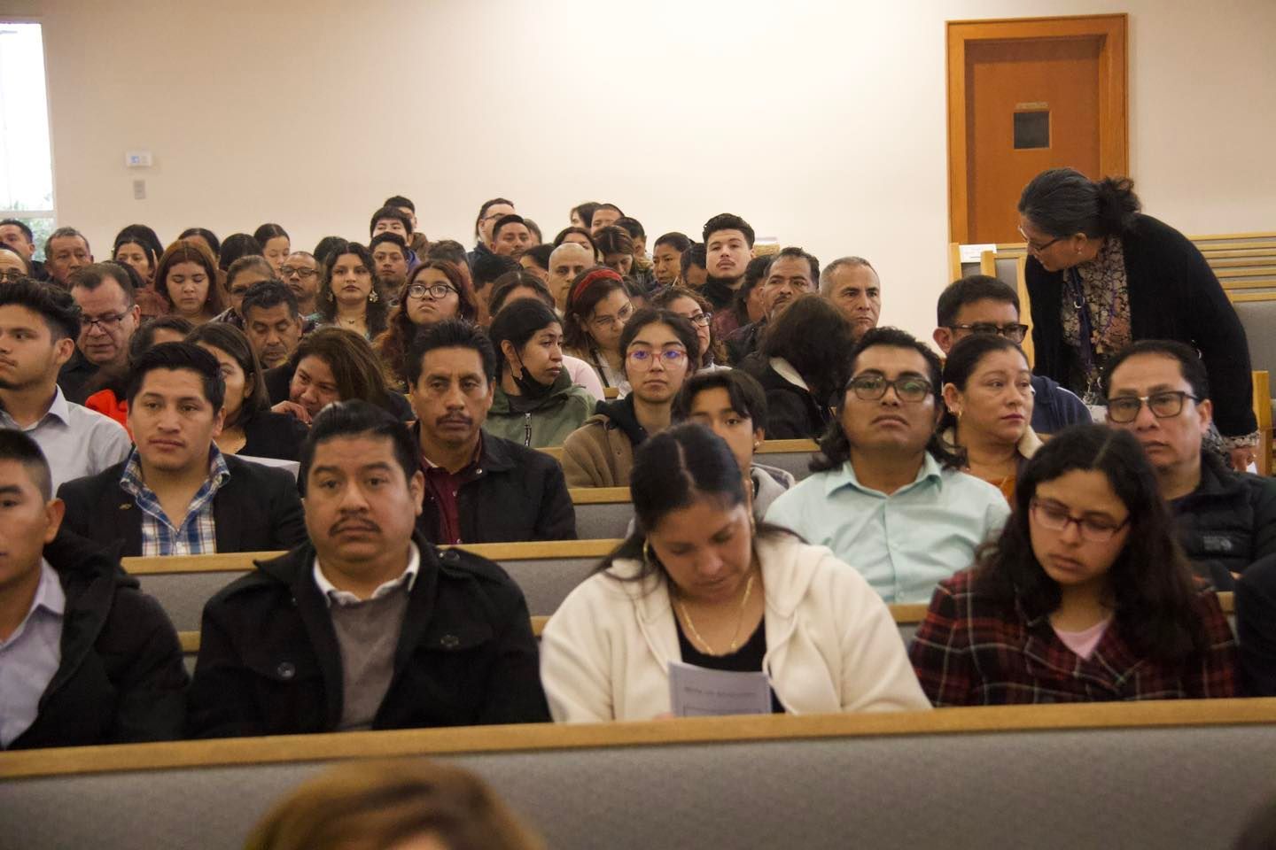 Audience seated in a lecture hall, listening attentively.