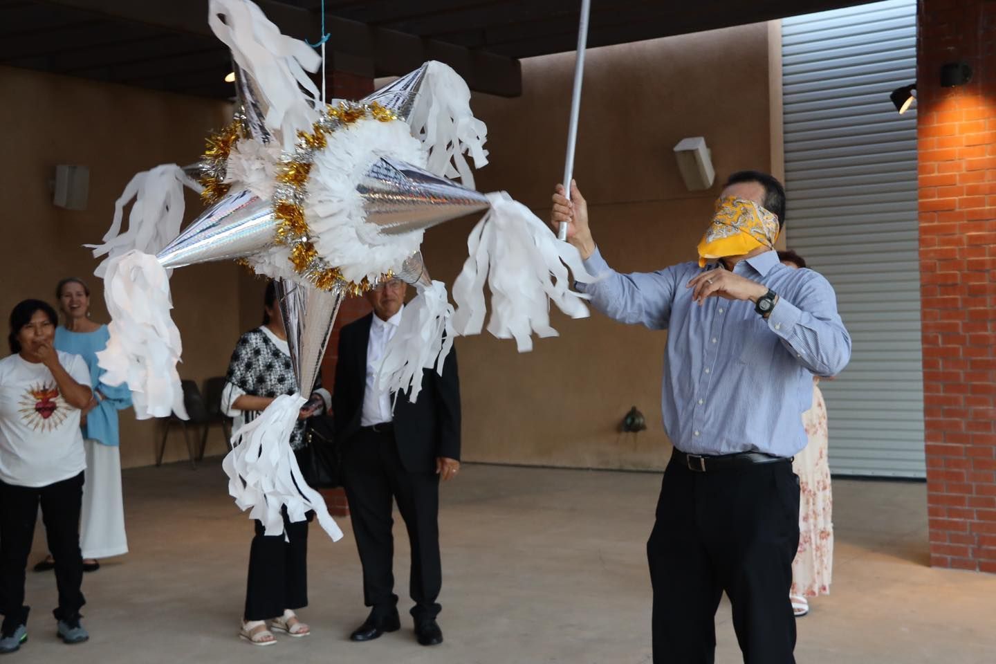 People carrying a large white bird puppet during an outdoor performance under a covered walkway