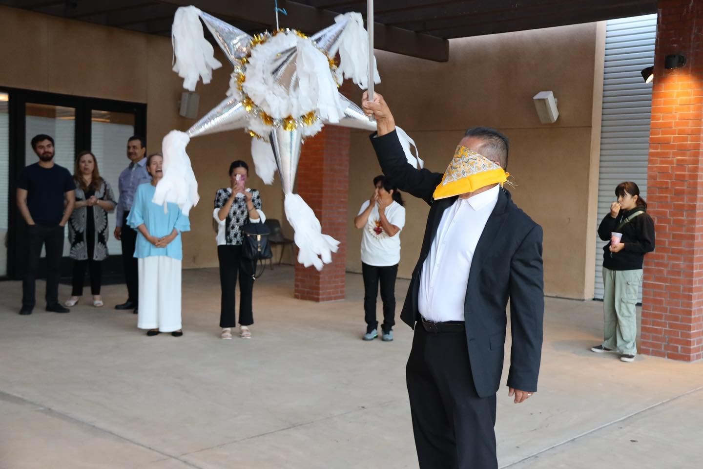 Person in black suit holds up a white dove-shaped decoration at an outdoor ceremony.