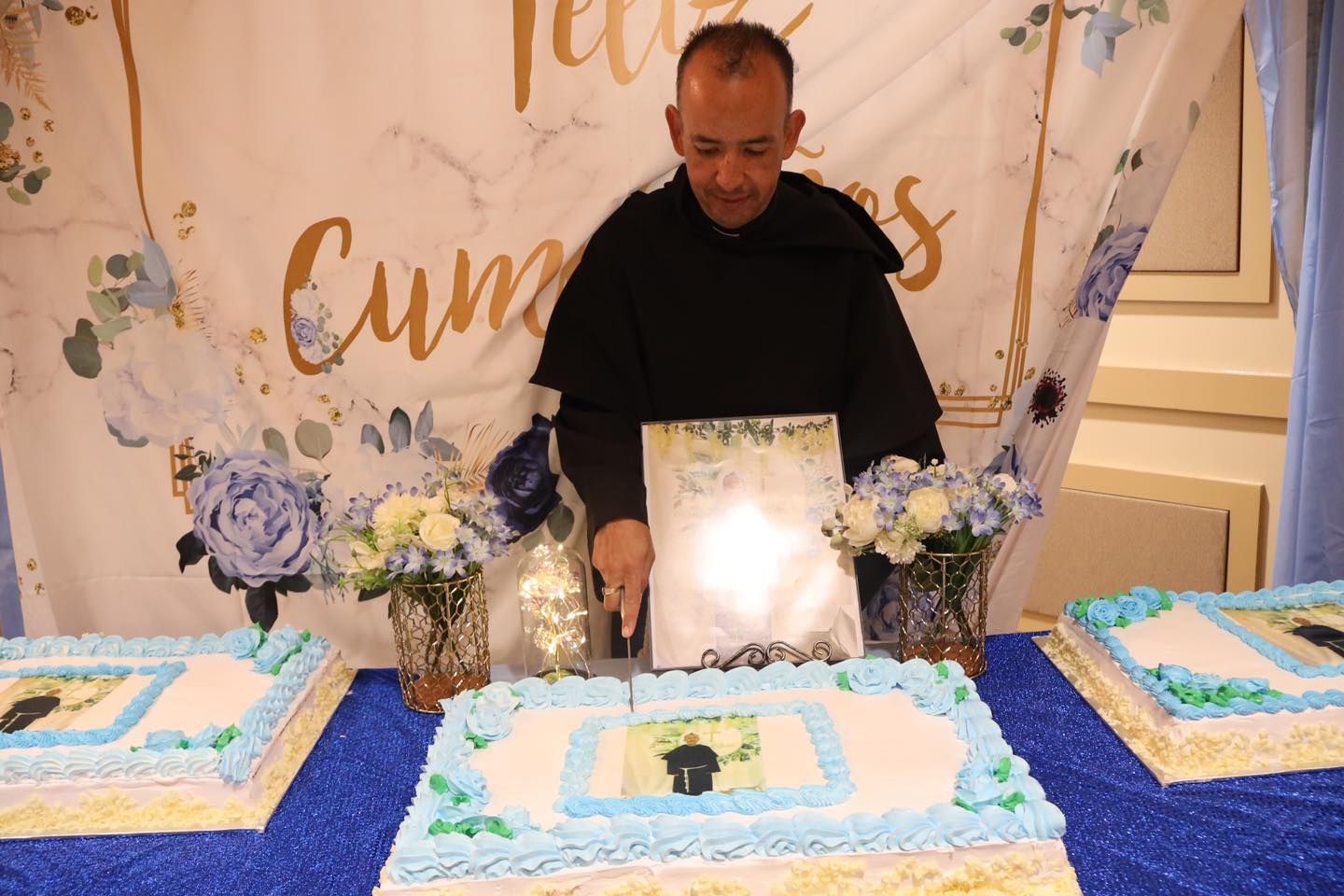 Man standing behind three decorated cakes at a blue-themed birthday dessert table