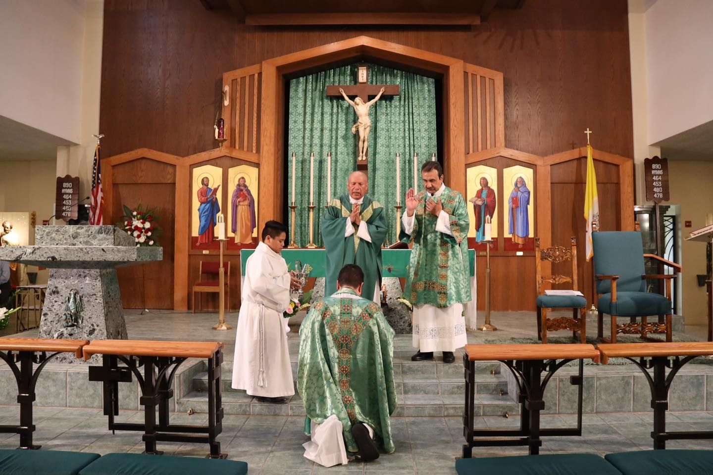 Priests in green vestments celebrate Mass at the altar inside a church sanctuary