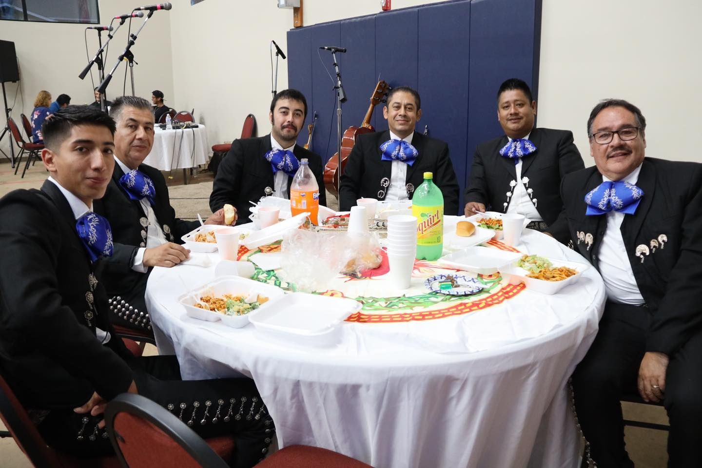 Five people in suits sit around a decorated table at a formal event, smiling at the camera.