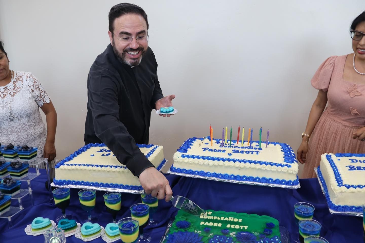 Man serving cupcakes from a blue-and-white dessert table at a celebration