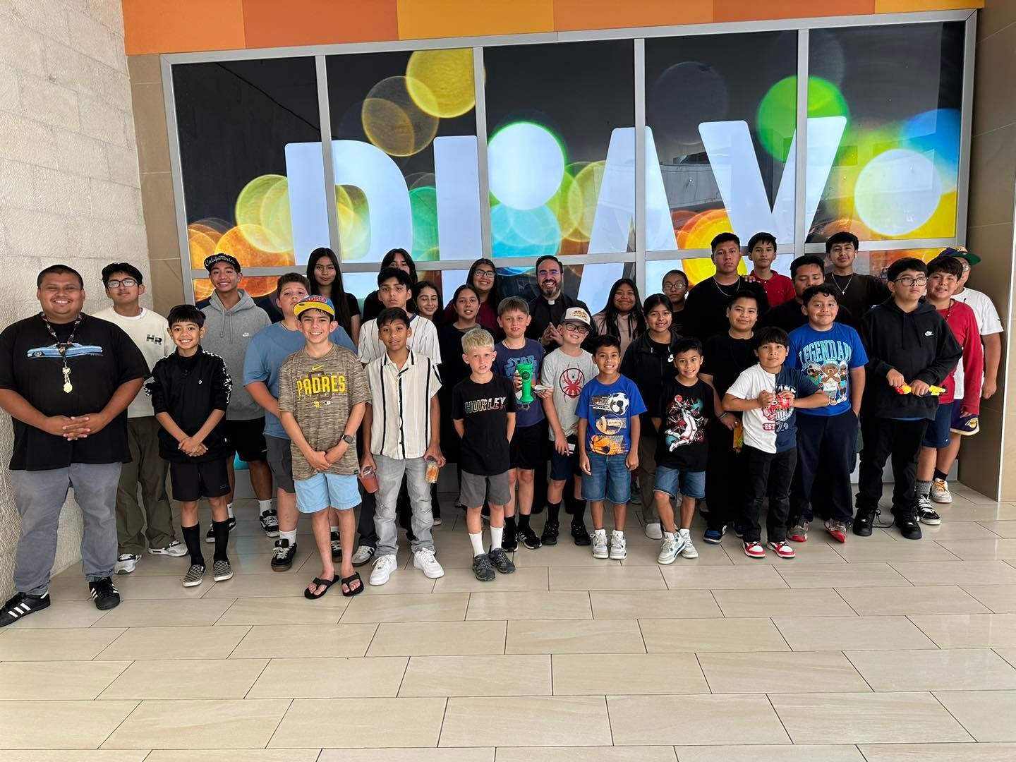 Group of people posing in front of a colorful wall mural indoors