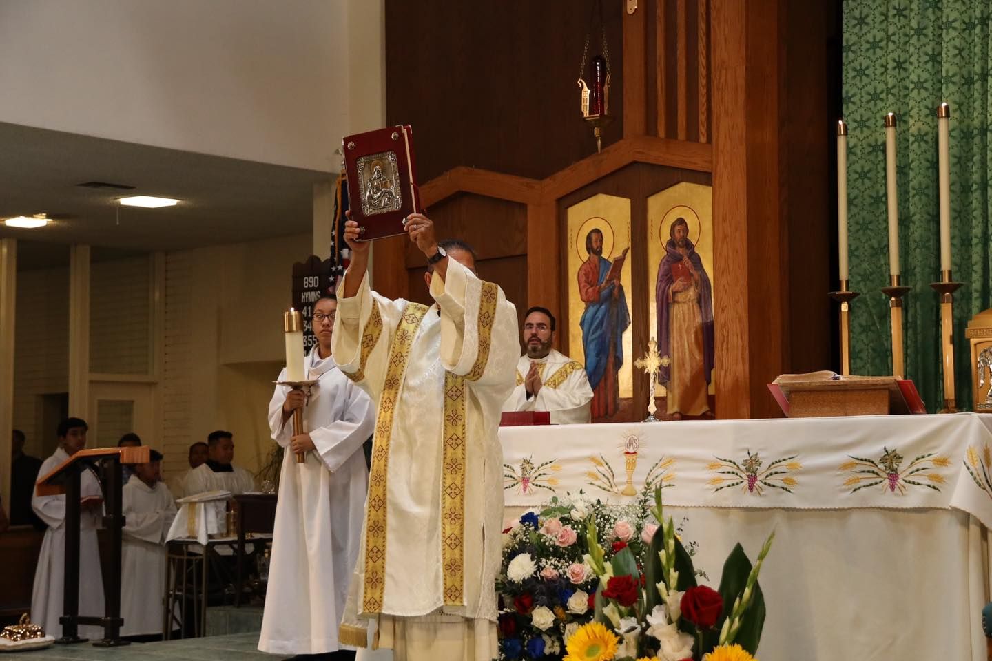 Priest holding up a sacred book during a church service at the altar