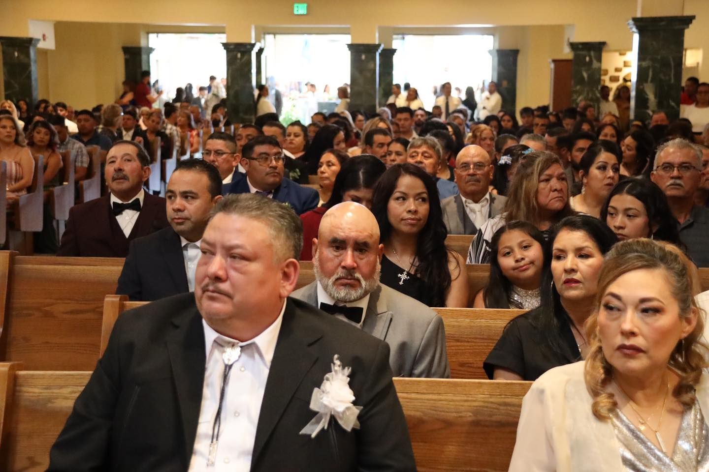 Audience seated in a formal ceremony, with guests facing the front in a crowded hall.