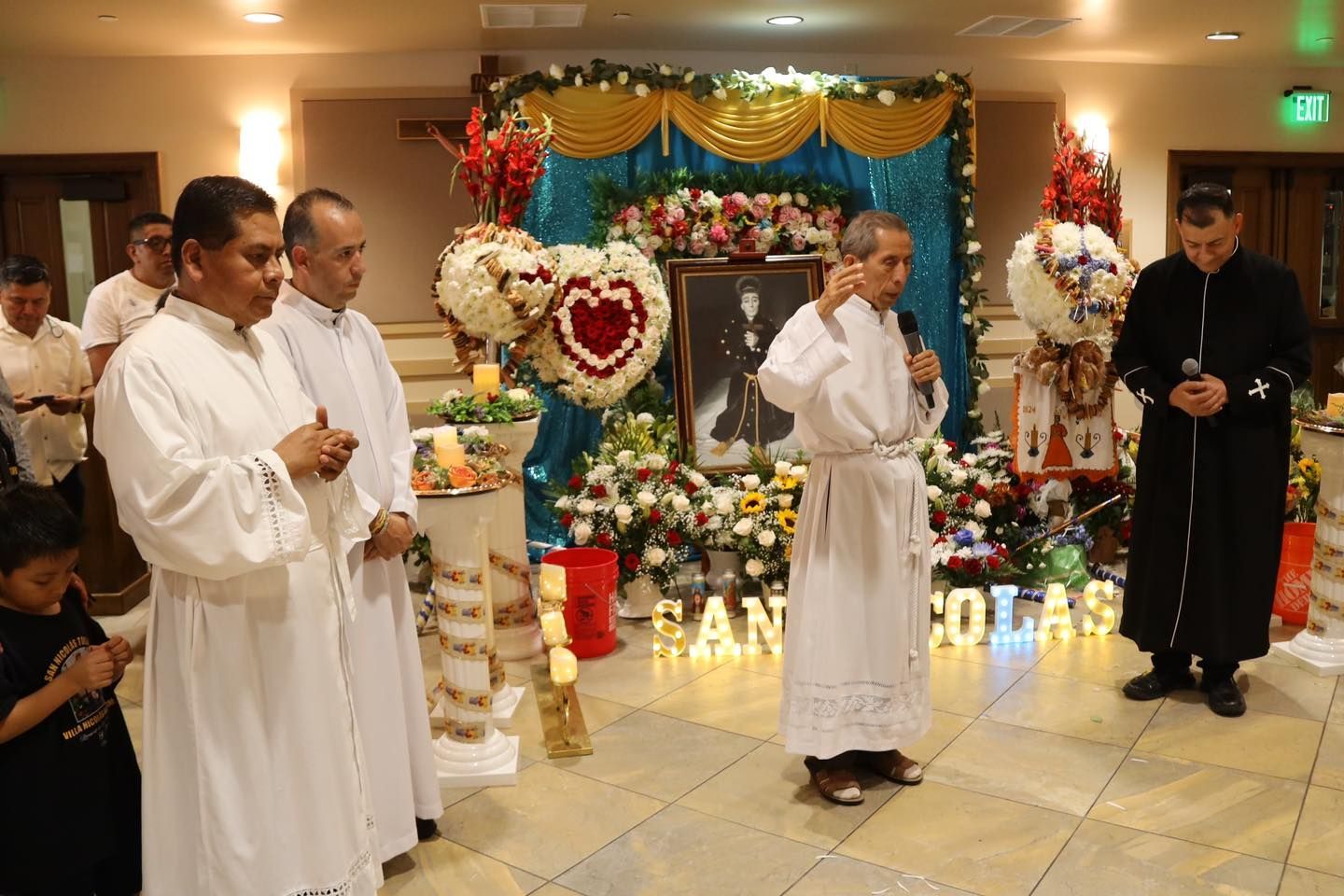 People in white robes standing before a decorated altar in a church-like hall