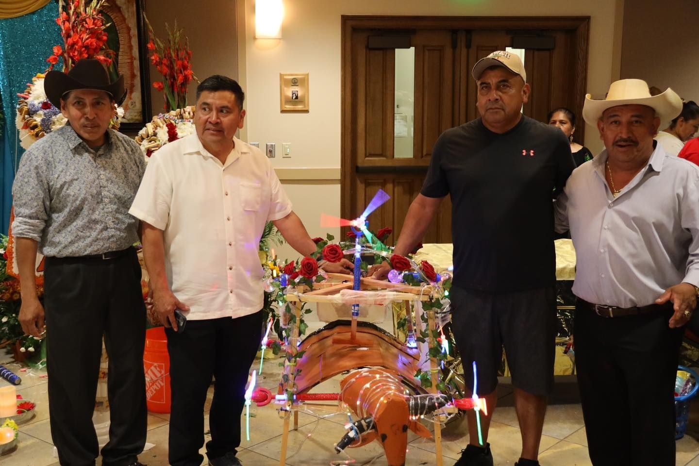 Four people standing indoors beside a decorated animal display with colorful lights