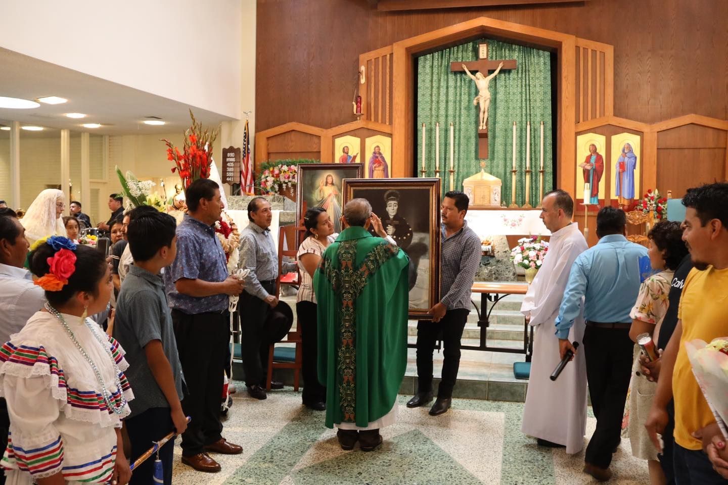 Church ceremony with priest in green vestments speaking before the altar, surrounded by congregants