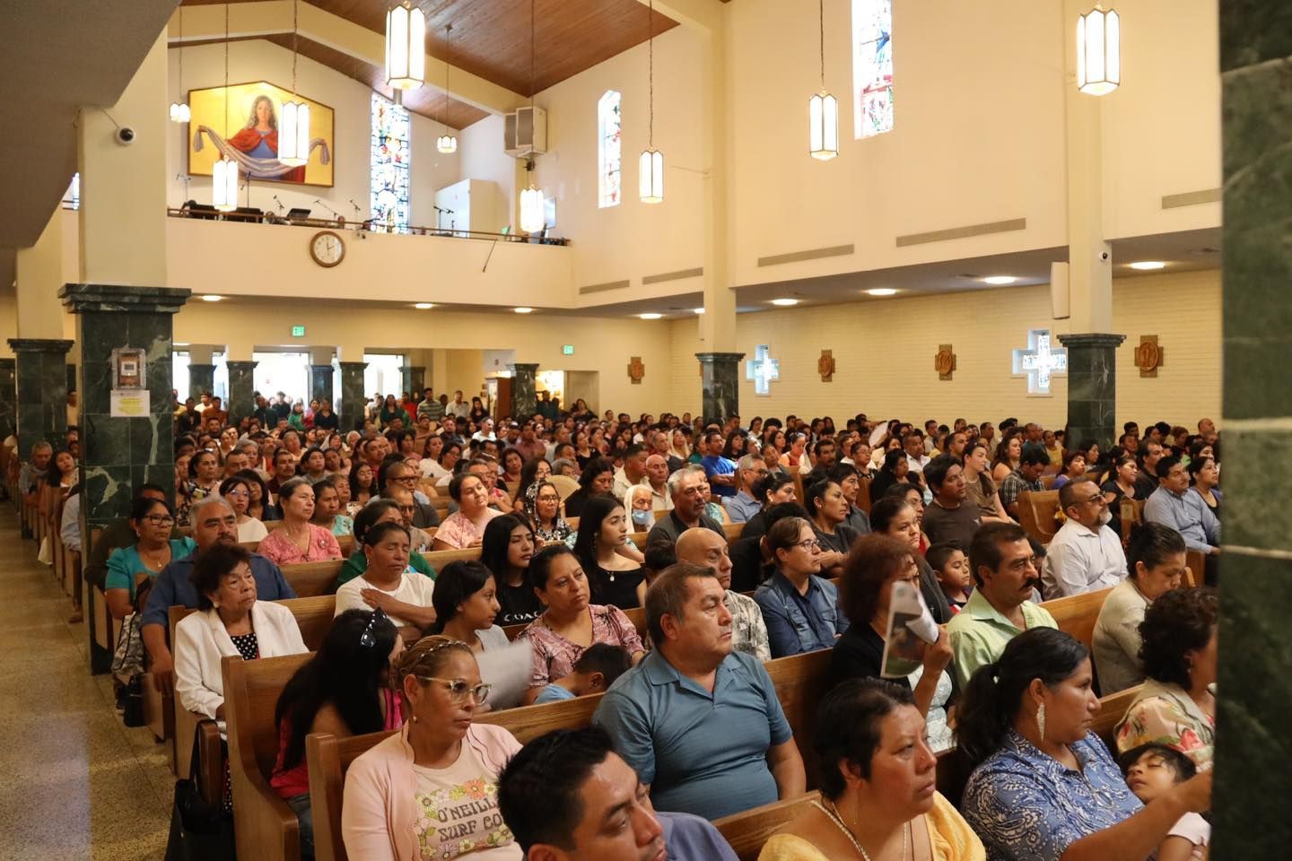 Large congregation seated inside a bright church, facing the front during a service.