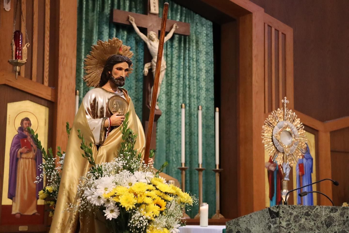 Religious altar with a statue of Jesus, crucifix, candles, and flowers in a church sanctuary