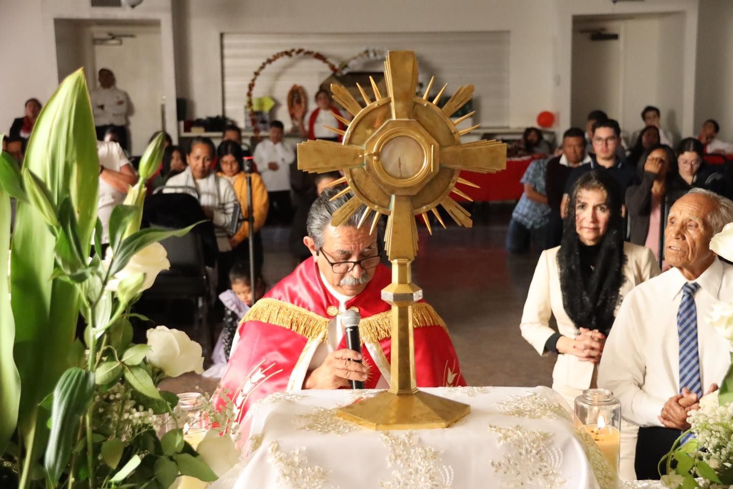 Religious ceremony with priest before a gold monstrance, surrounded by worshippers in a church