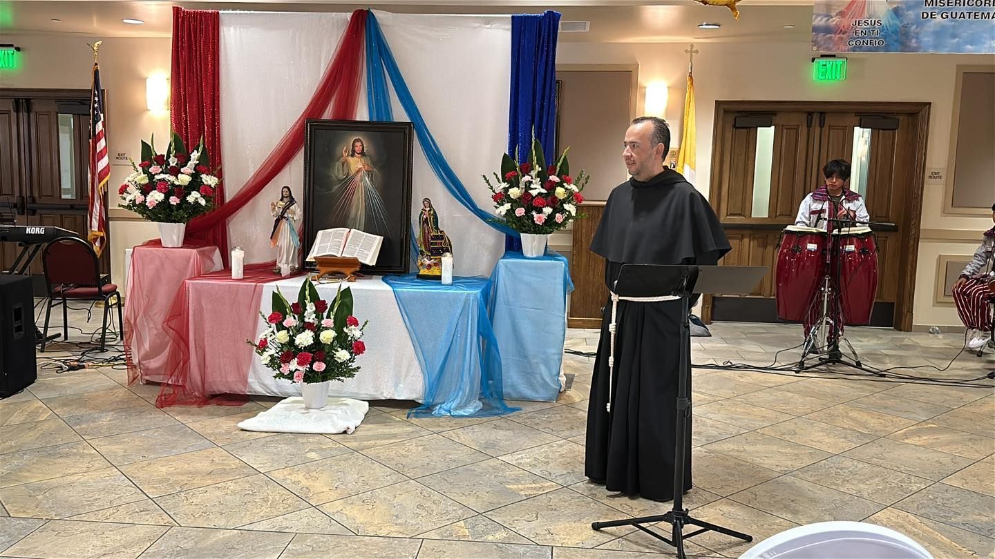 Memorial display with flowers and photos in a banquet hall; a robed speaker stands at a microphone.