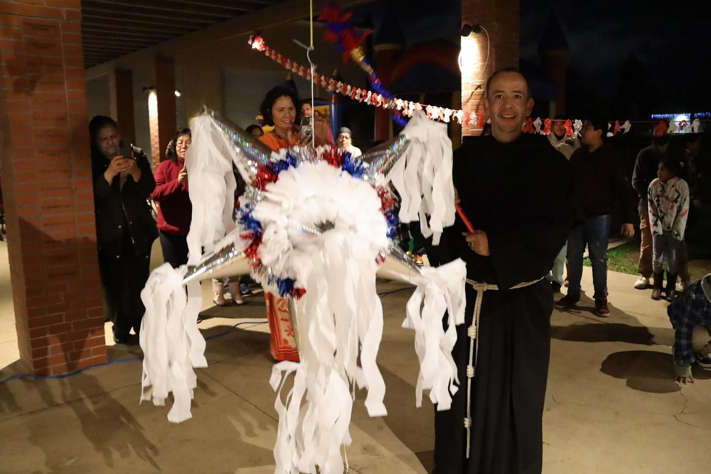 Person holding a white, red, and blue carnival costume with streamers at a nighttime outdoor event