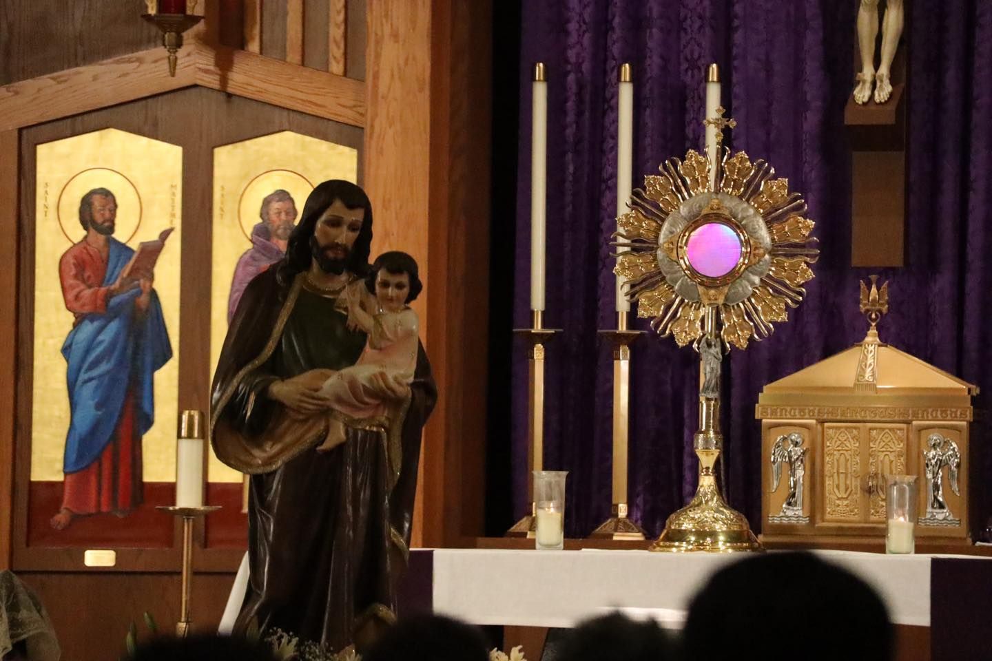 Church altar with statue of Mary and child beside a lit monstrance and candles.
