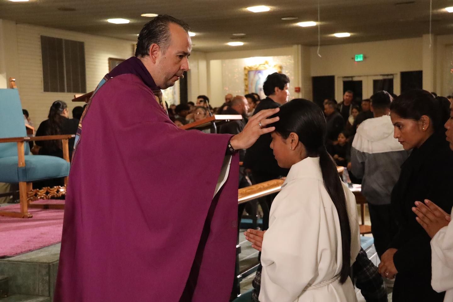 Priest in purple robe blessing a person during a church ceremony