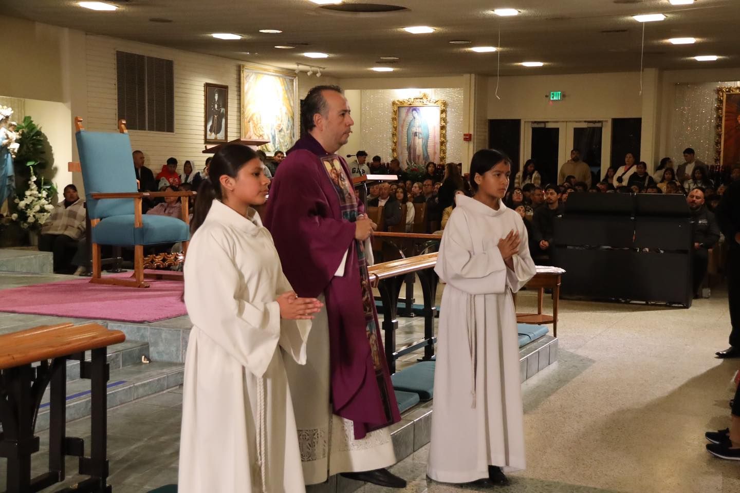 Three people in white and purple robes standing in a church during a service