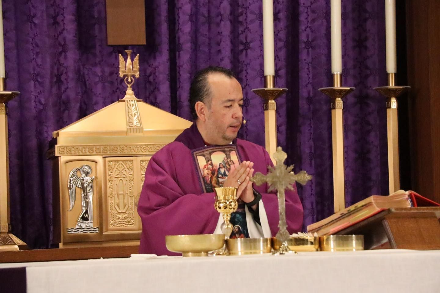 Priest in purple vestments at altar, holding a chalice during Mass