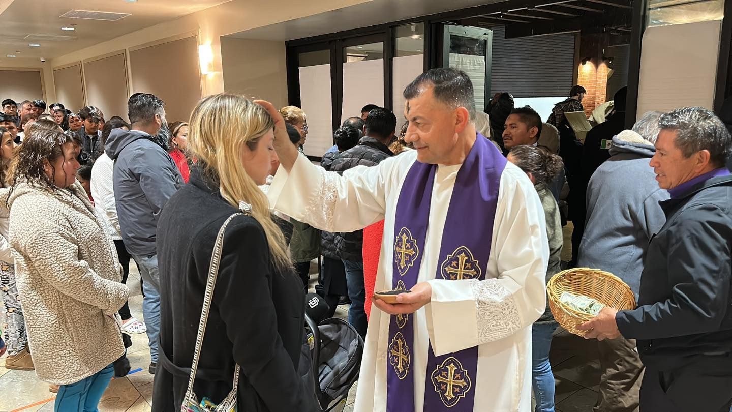 Priest in purple stole blessing people at a church reception inside a hall