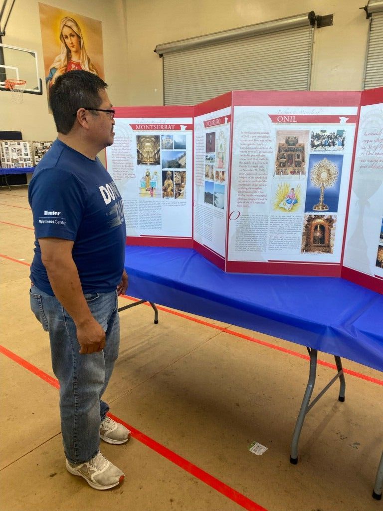 Man viewing a tri-fold display board at a table in a room with blue and red accents