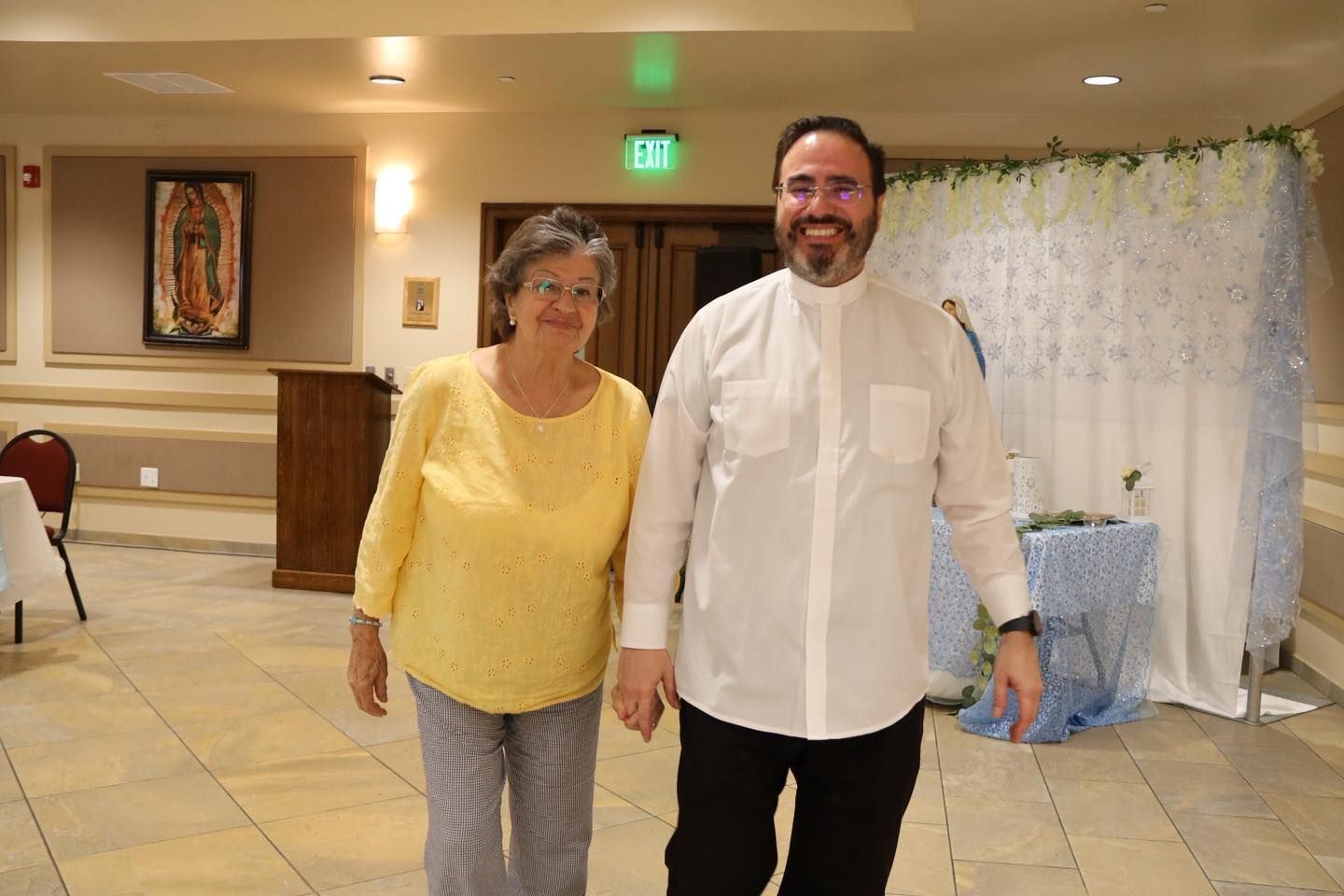 Two people smiling and walking in a decorated indoor hall