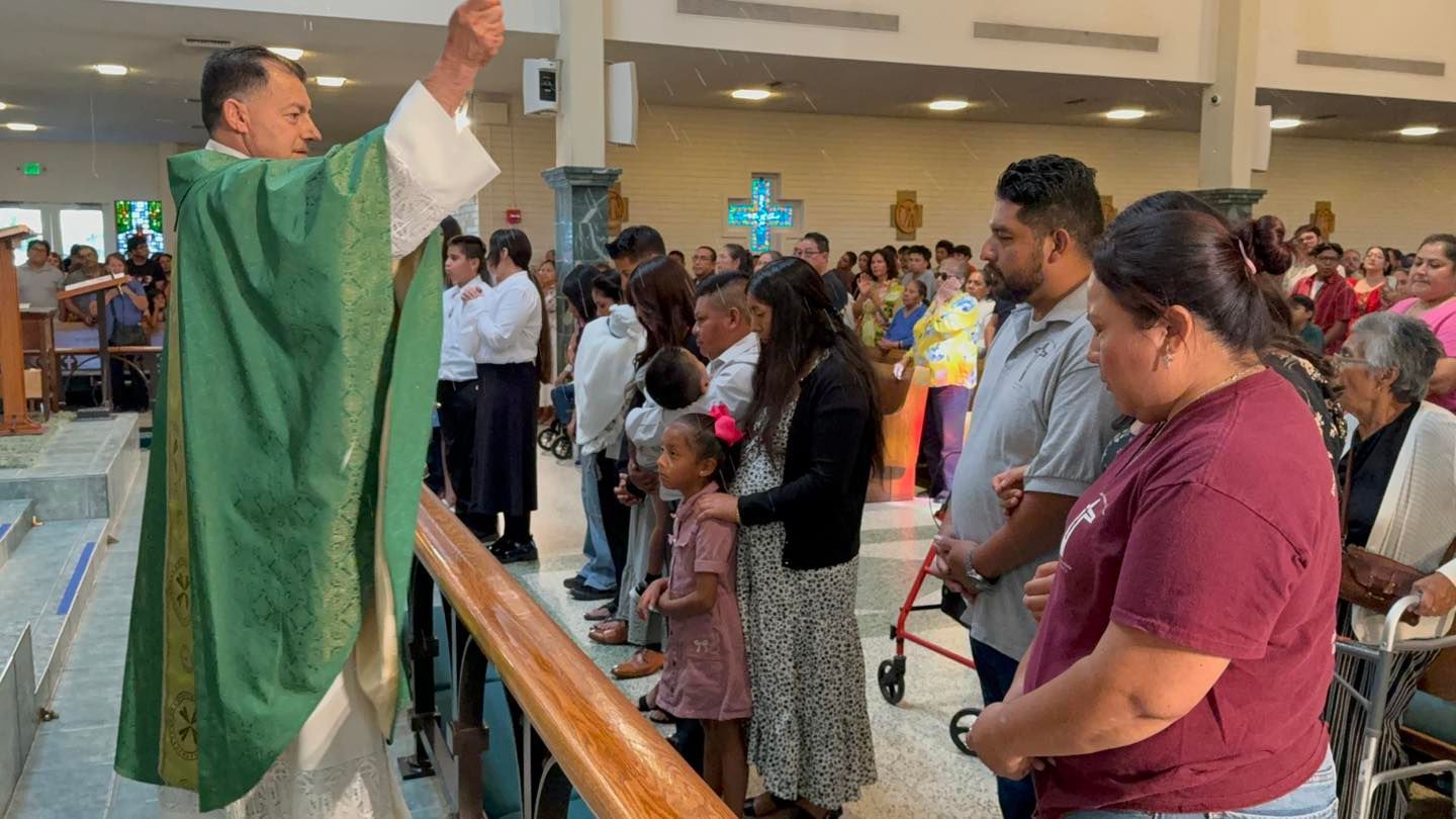 Priest in green vestments blessing a congregation during church service