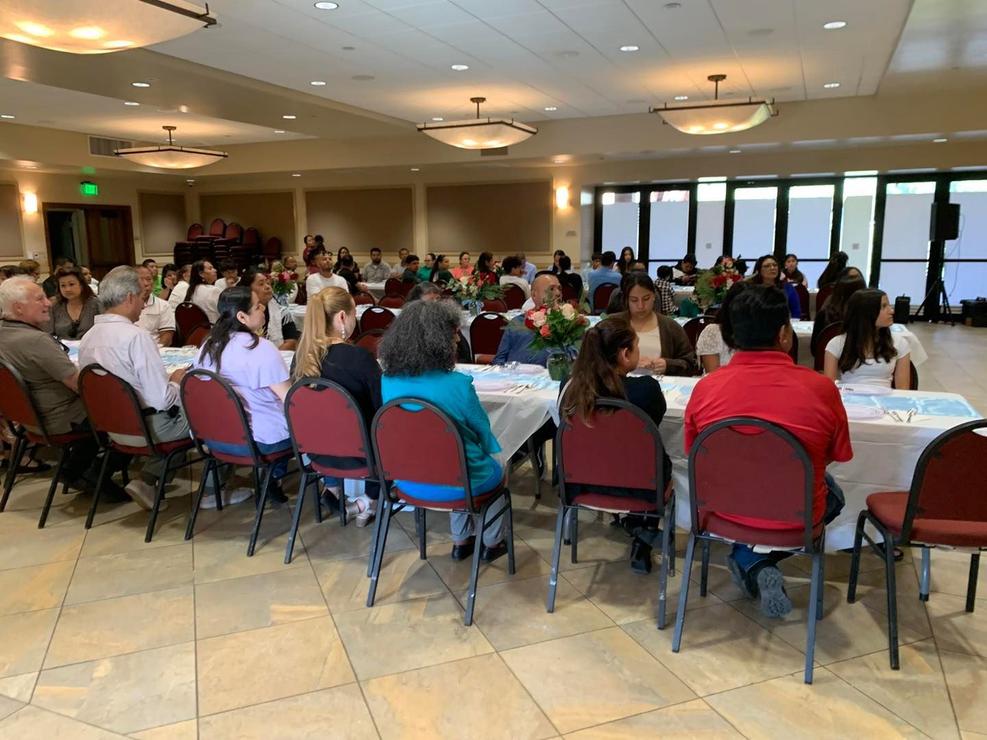 People seated at round tables in a banquet hall during a large indoor event
