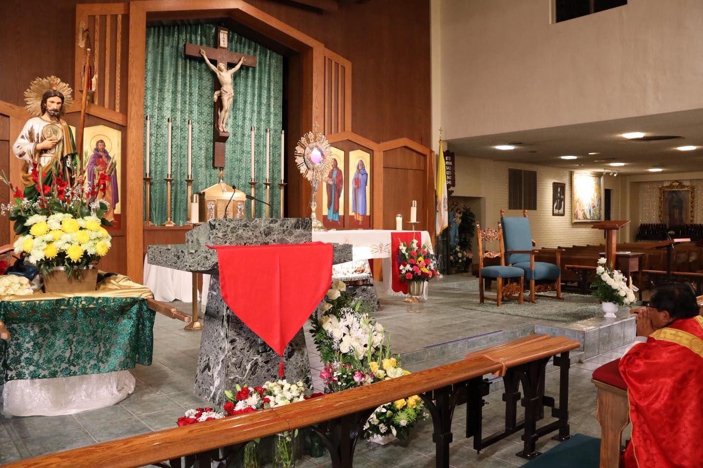 Church altar with crucifix, red cloth, flowers, and candles in a chapel interior