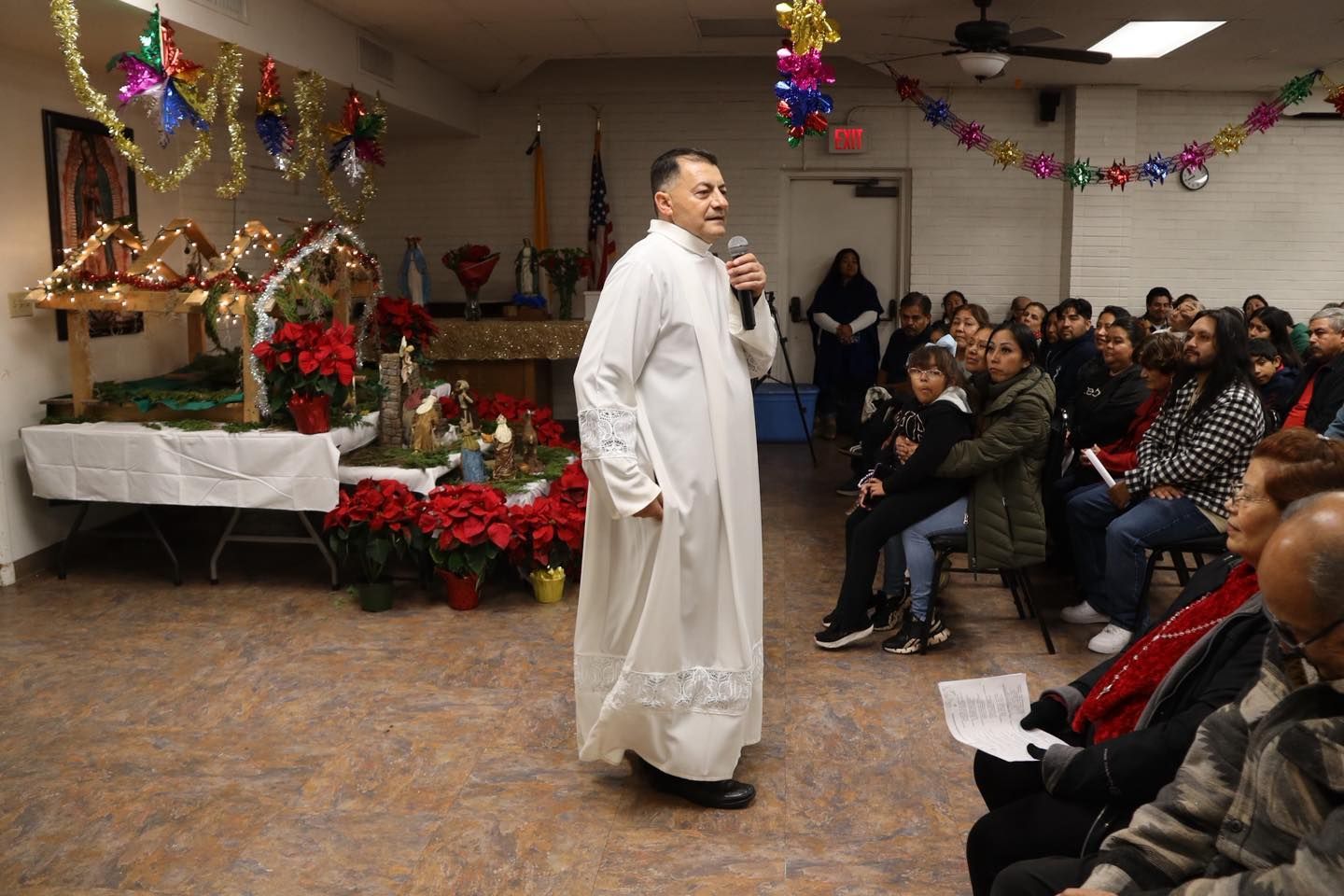Man speaking in a decorated room to an audience seated on folding chairs