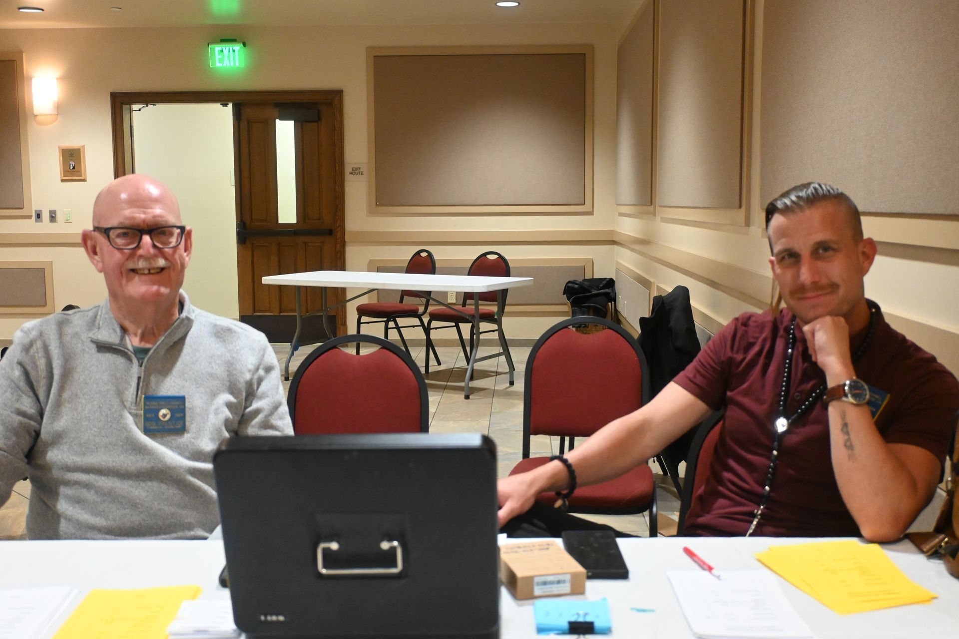 Two people seated at a table with a laptop in a conference room