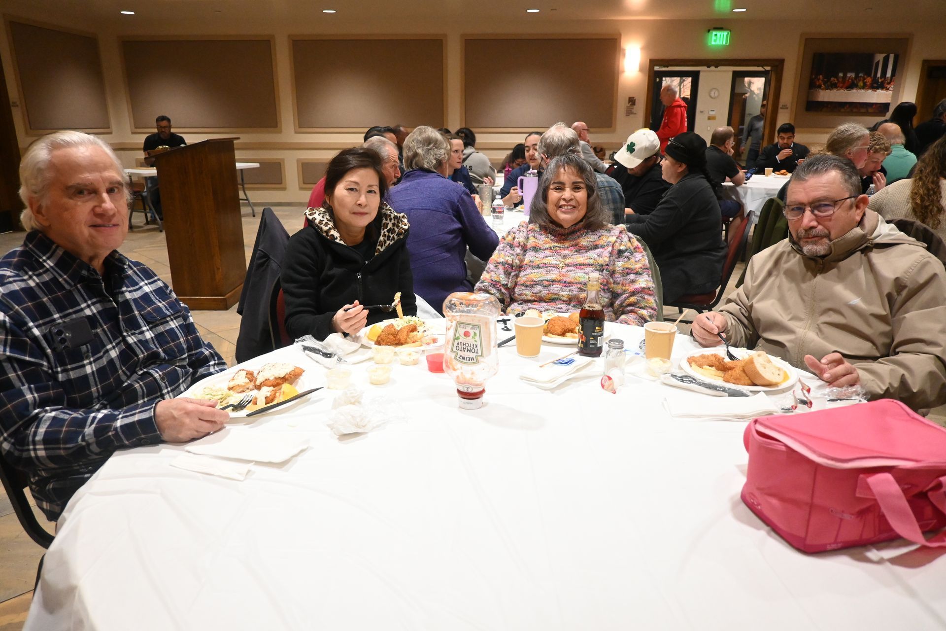 People seated at a banquet table with food and drinks in a hall