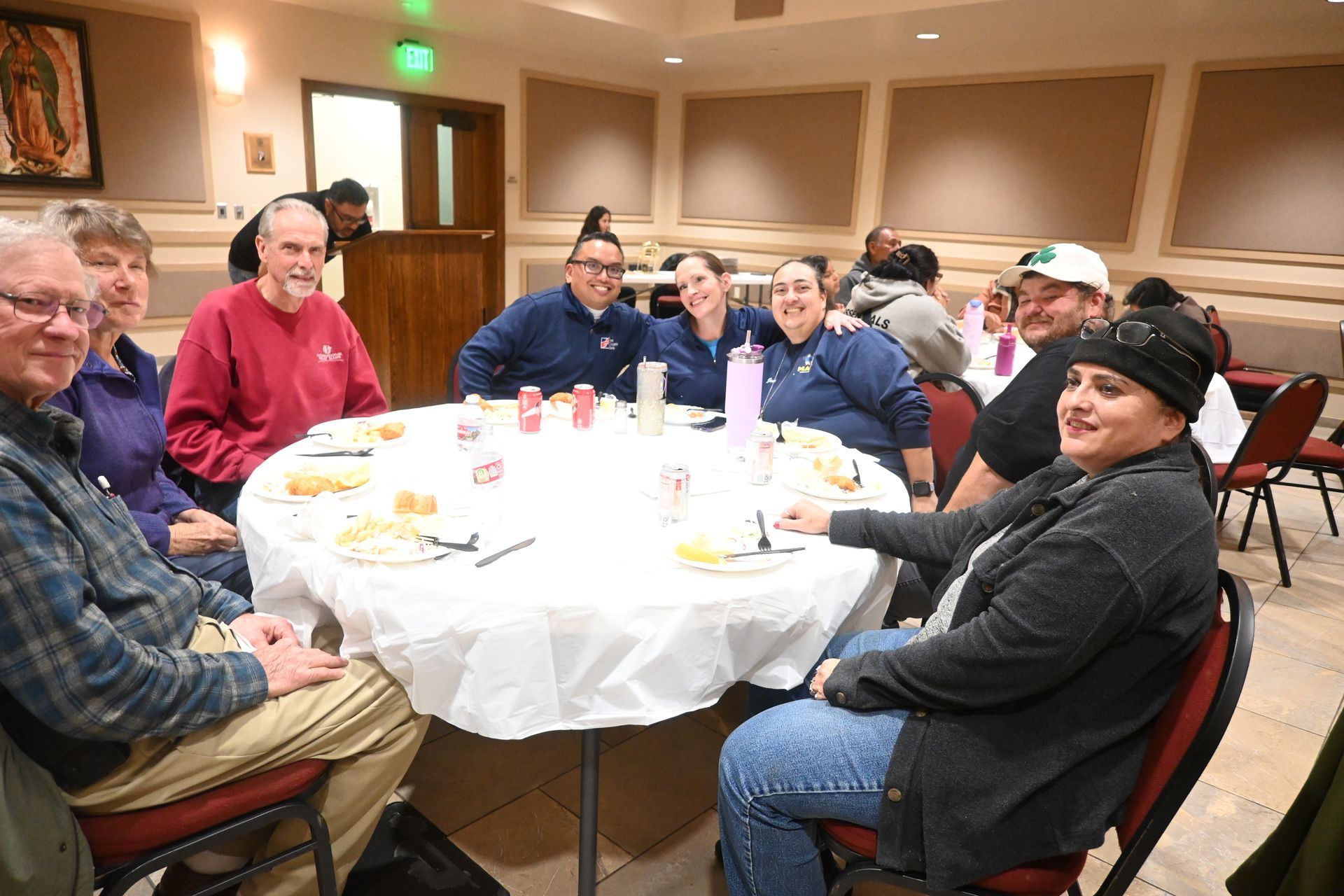 People seated around a round table at a banquet, smiling in a warmly lit hall.