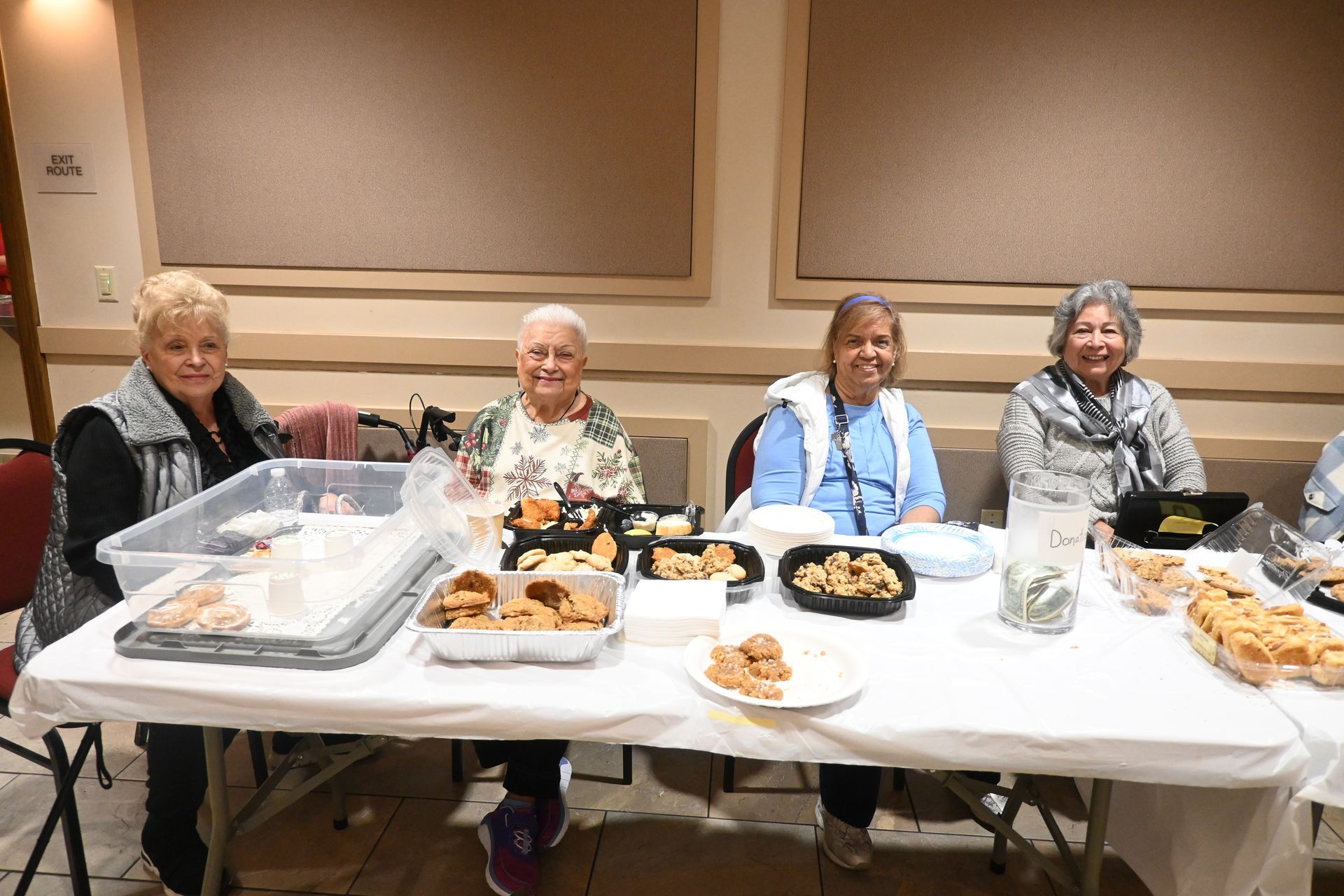 Four people seated at a banquet table with trays of food and dessert in a banquet room