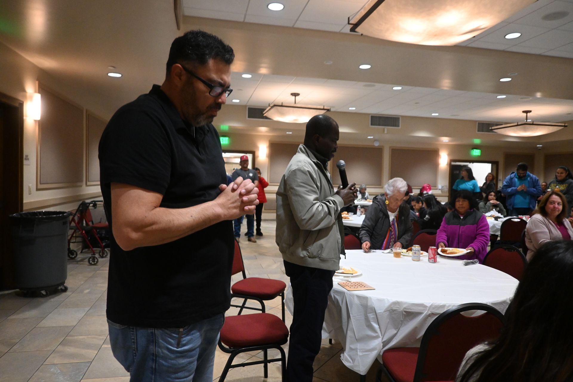 Two people speaking to a seated audience at a banquet table in a conference room