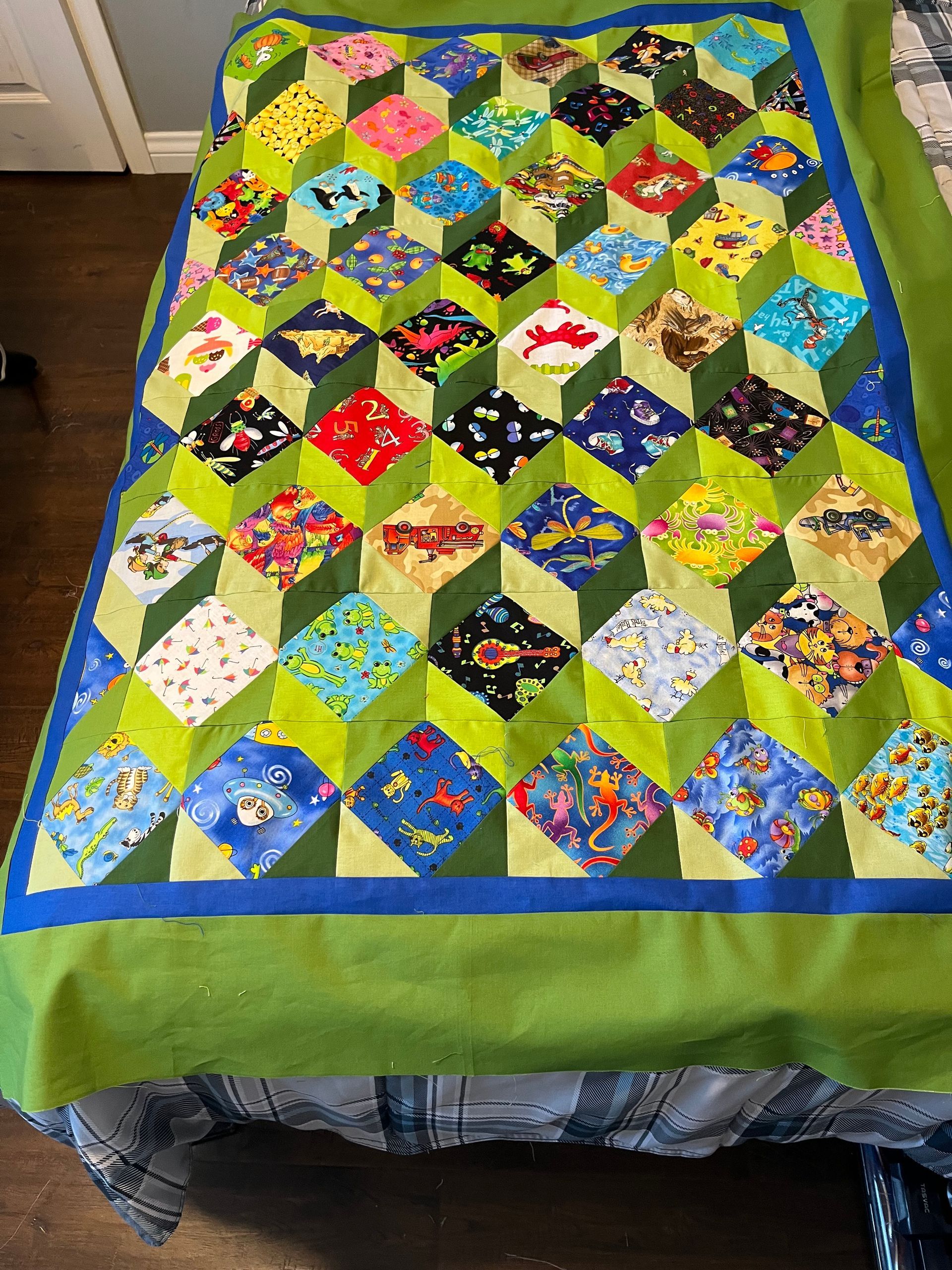 Colorful patchwork quilt with hexagon patterns on a bed, bordered in blue and green.