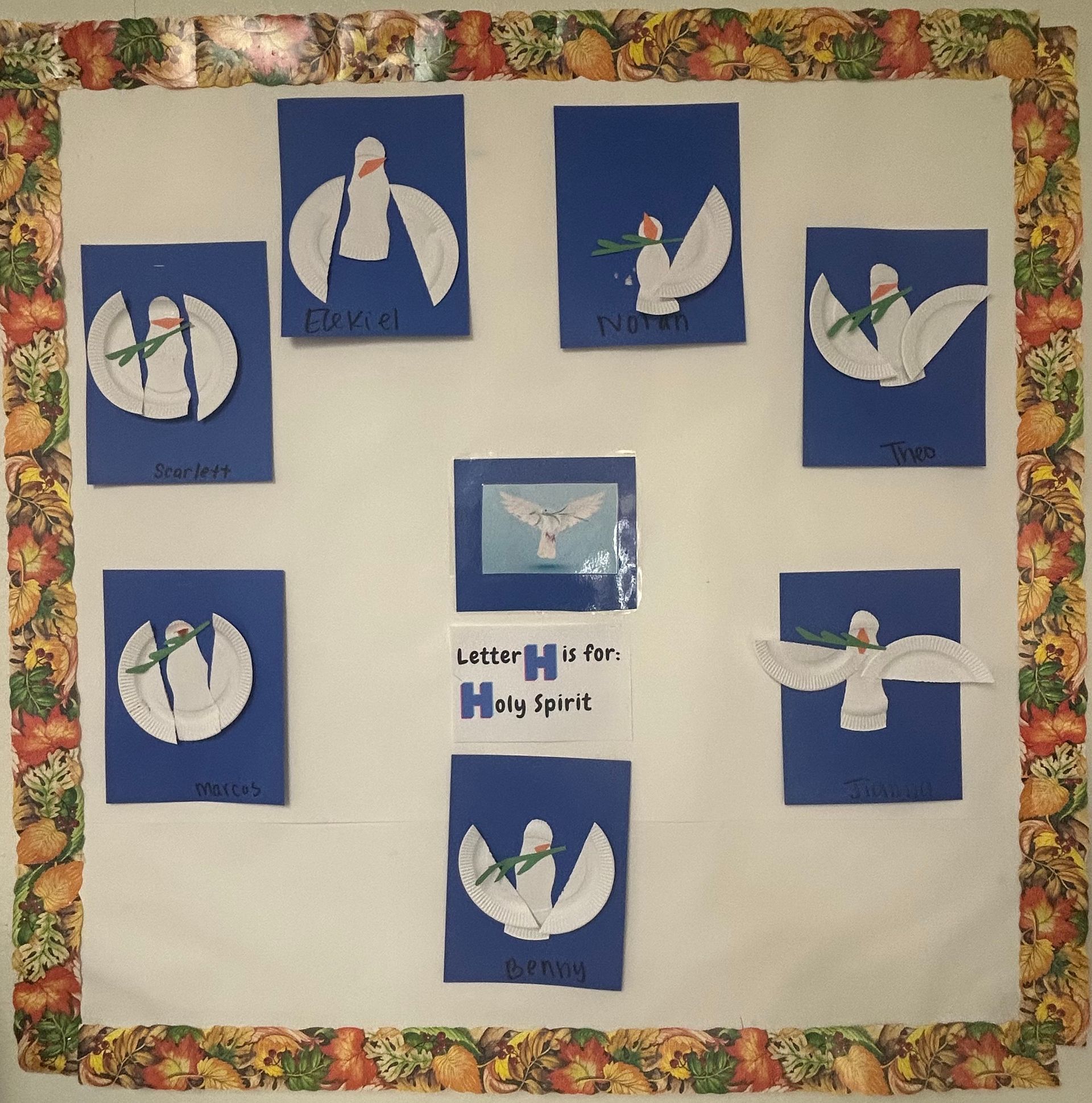 Blue paper crafts of white doves arranged on a display board with a small centered label.