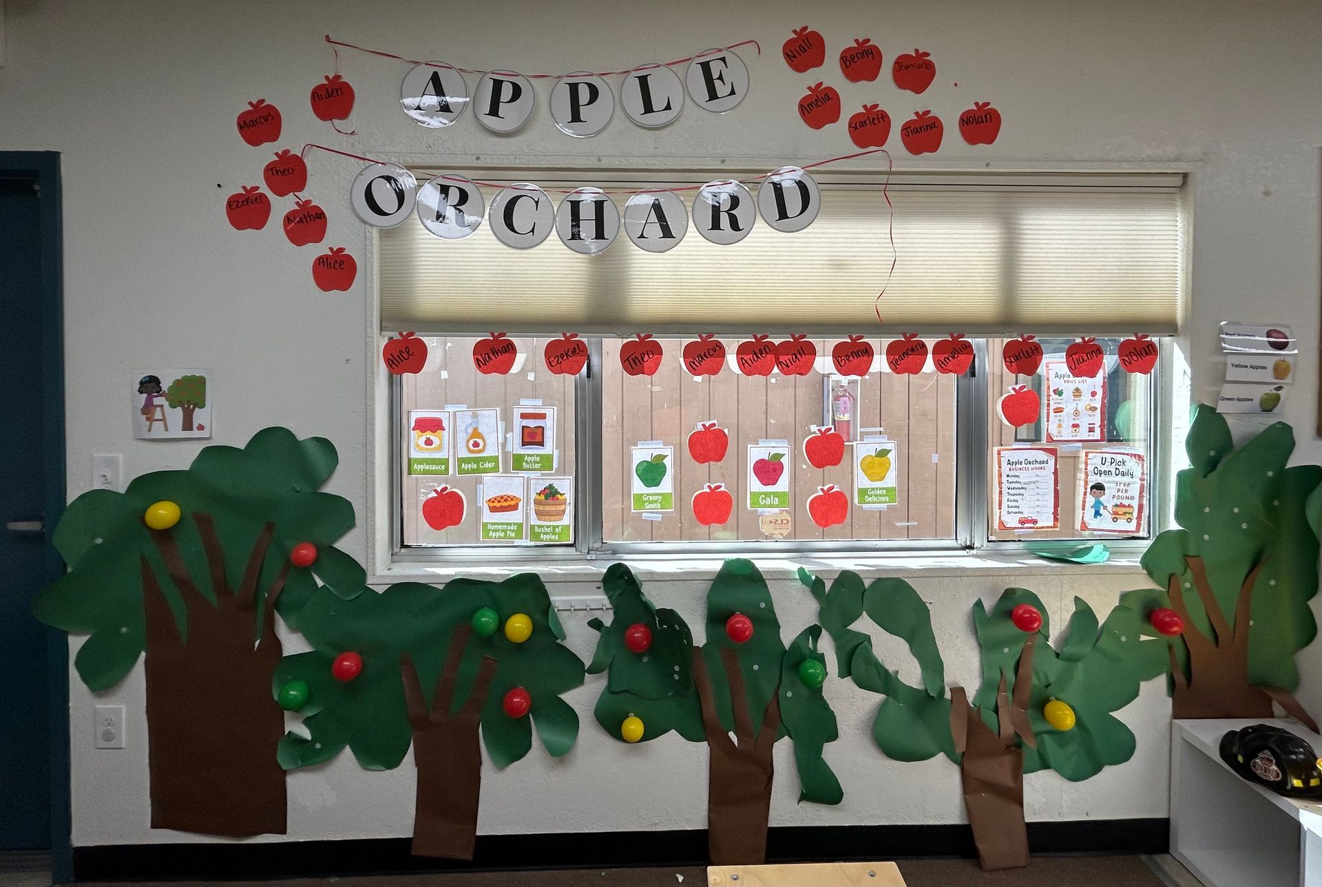 Classroom bulletin board with paper apples, trees, and a window display for an apple-themed lesson