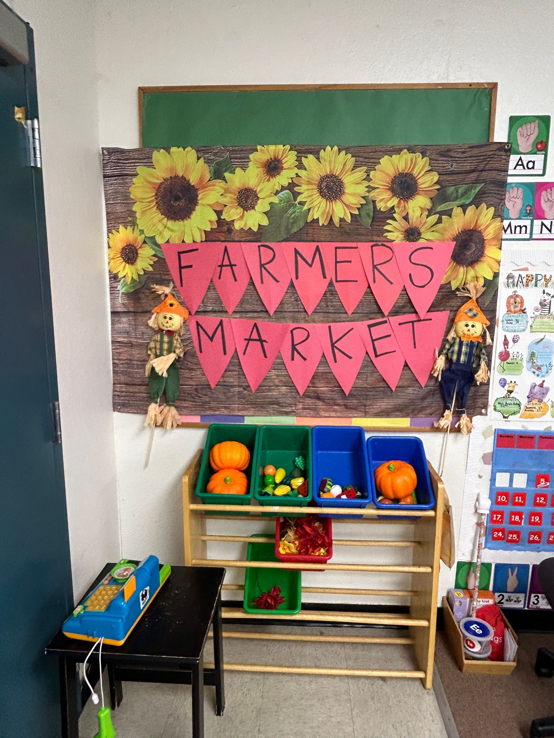 Colorful classroom farmers market display with sunflowers and a pink “FARMERS MARKET” sign