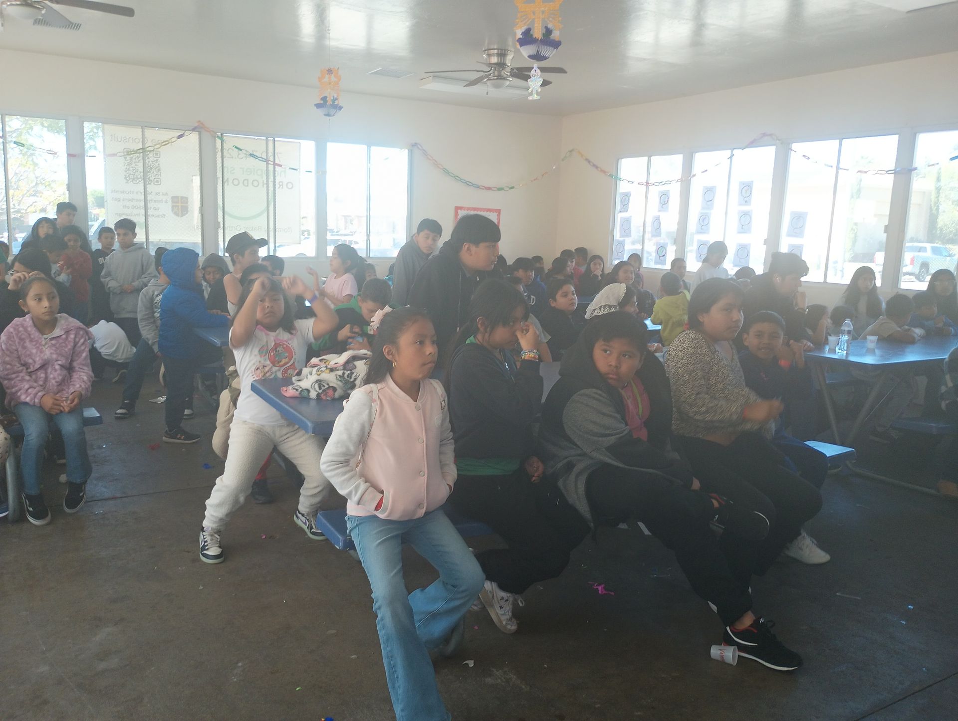 Audience seated in a bright hall, watching a presentation or performance
