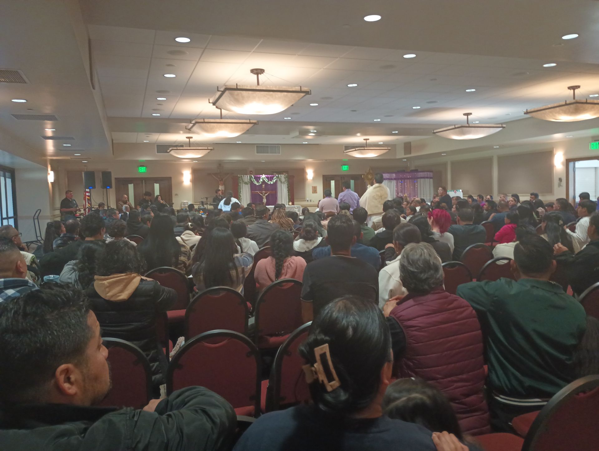 Crowded conference hall with seated audience facing a speaker at the front