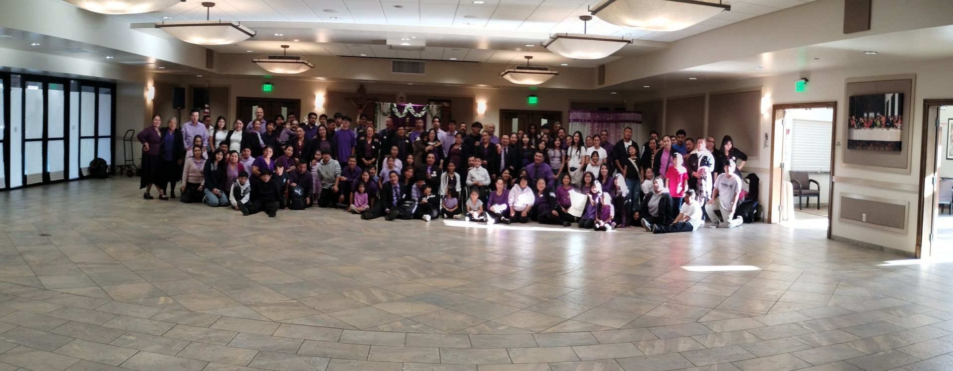 Large group posing for a photo in a spacious lobby with marble floors and a “Happy Halloween” banner