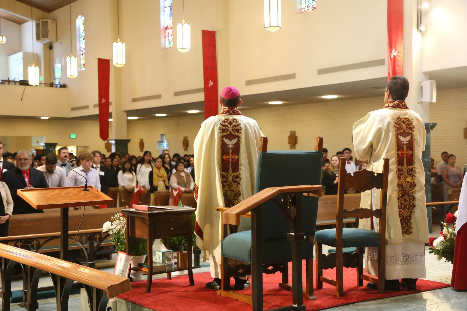 Church service viewed from the altar, with clergy facing a congregation in a decorated sanctuary.