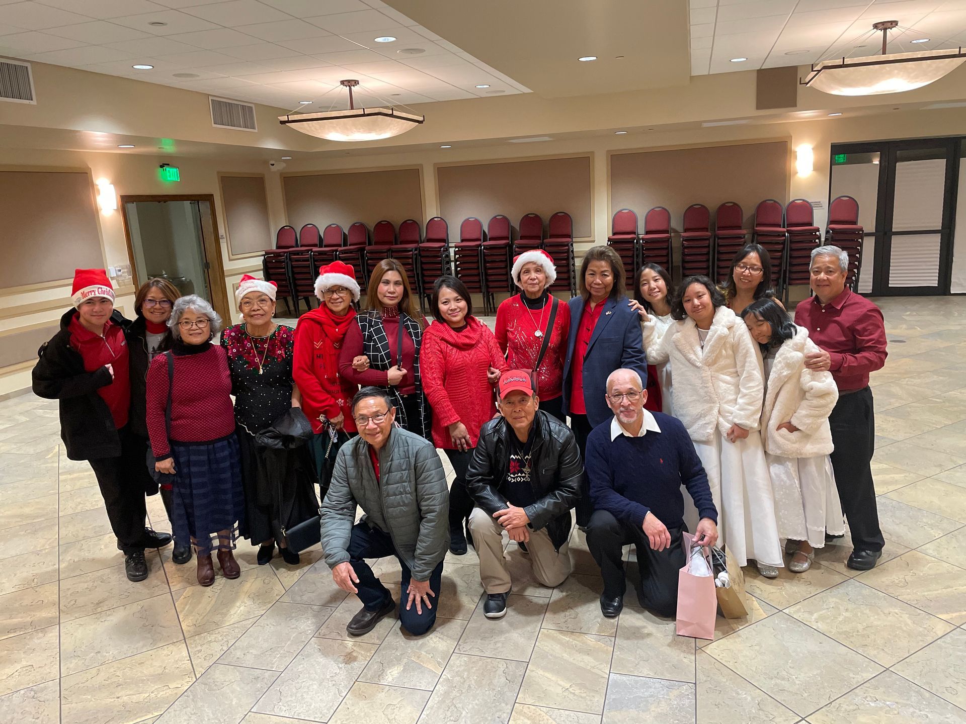 Group of people in red and white holiday outfits posing together in a lobby