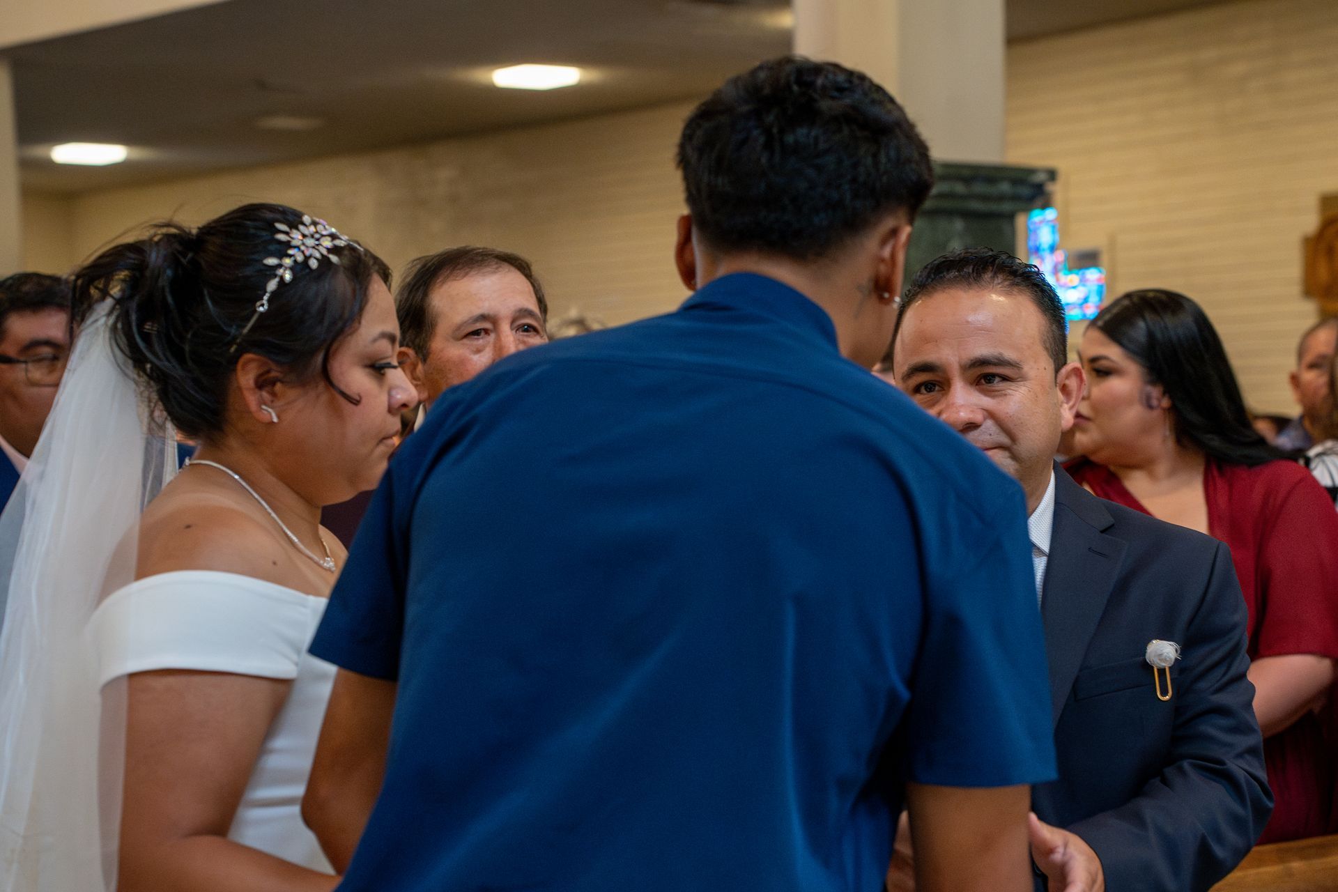 People in formal attire gathered at an indoor event, speaking in a small group.