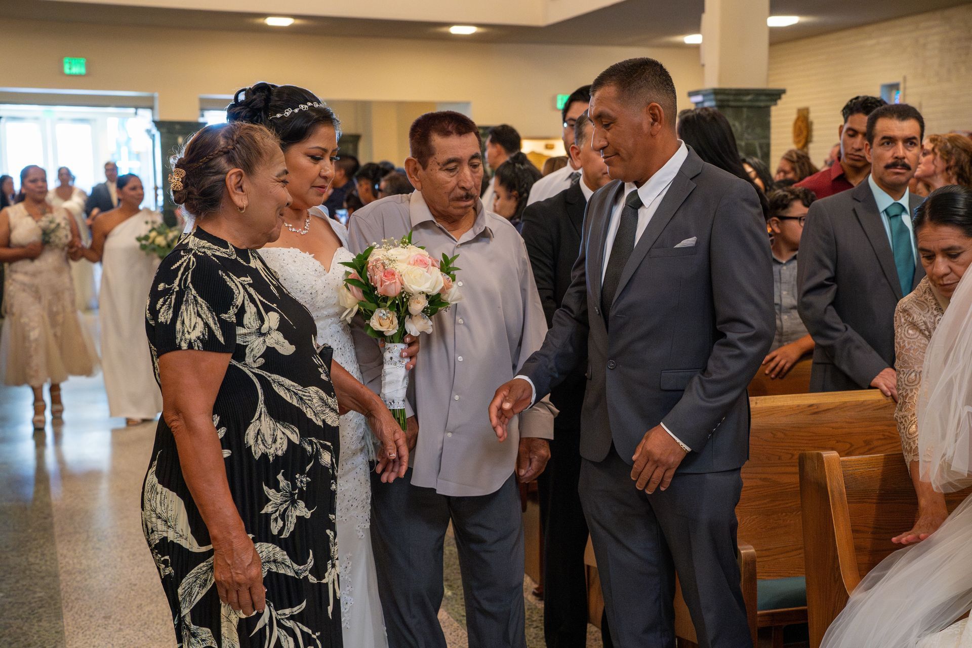 Guests gather in a church aisle during a wedding ceremony, with a couple standing near the pews.