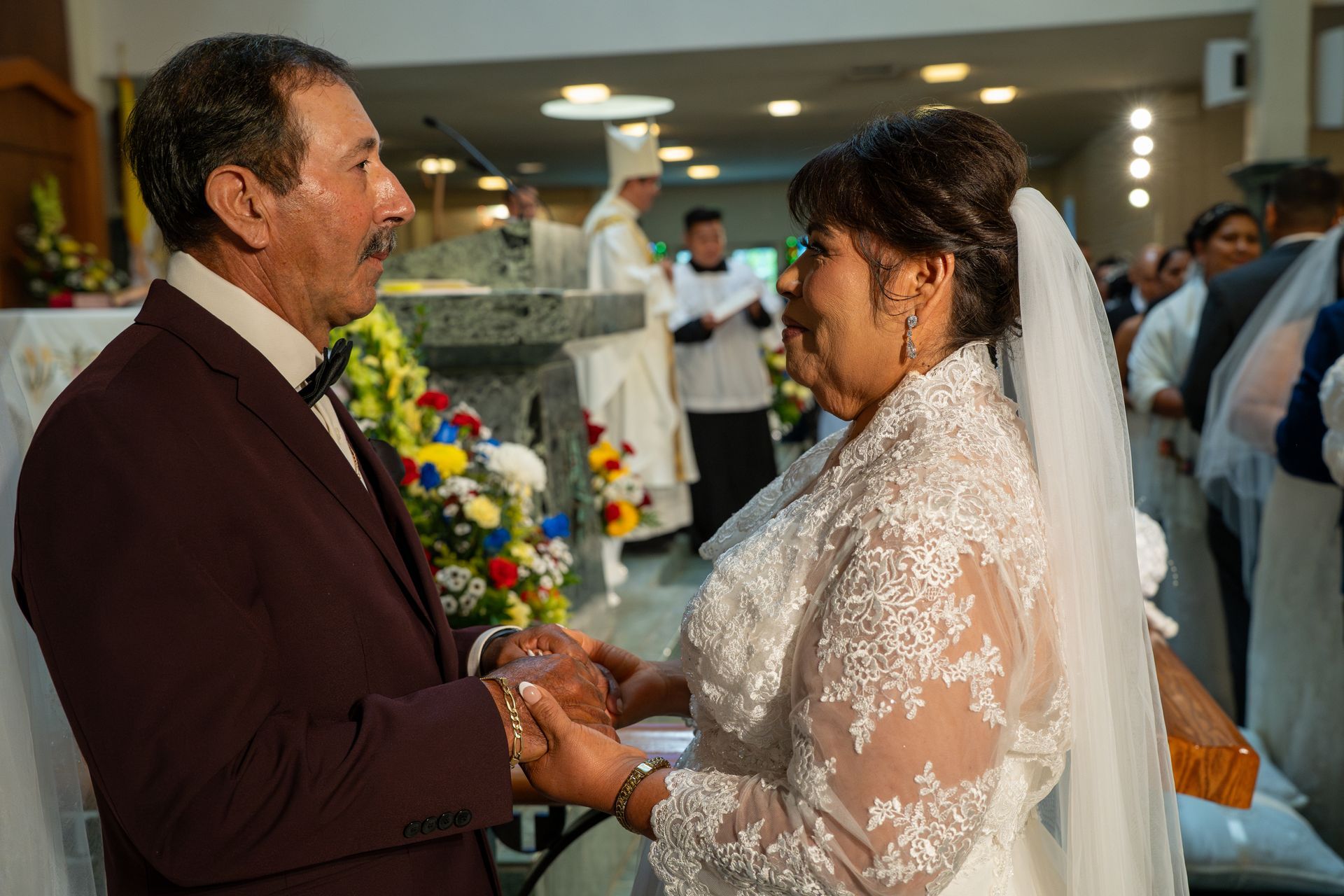 Bride and groom holding hands during a wedding ceremony in a church aisle