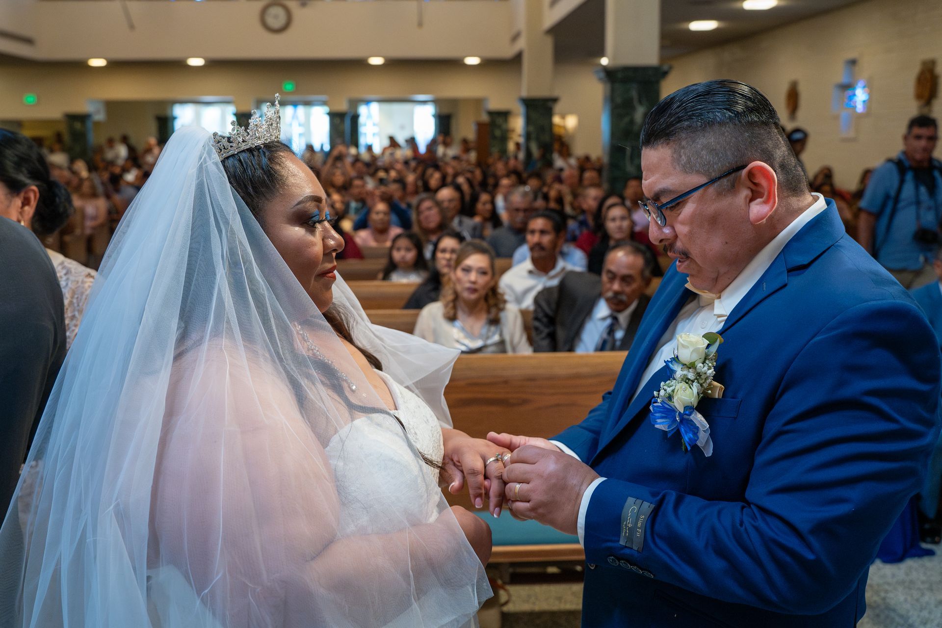 Bride and groom exchanging rings during a wedding ceremony in a church aisle
