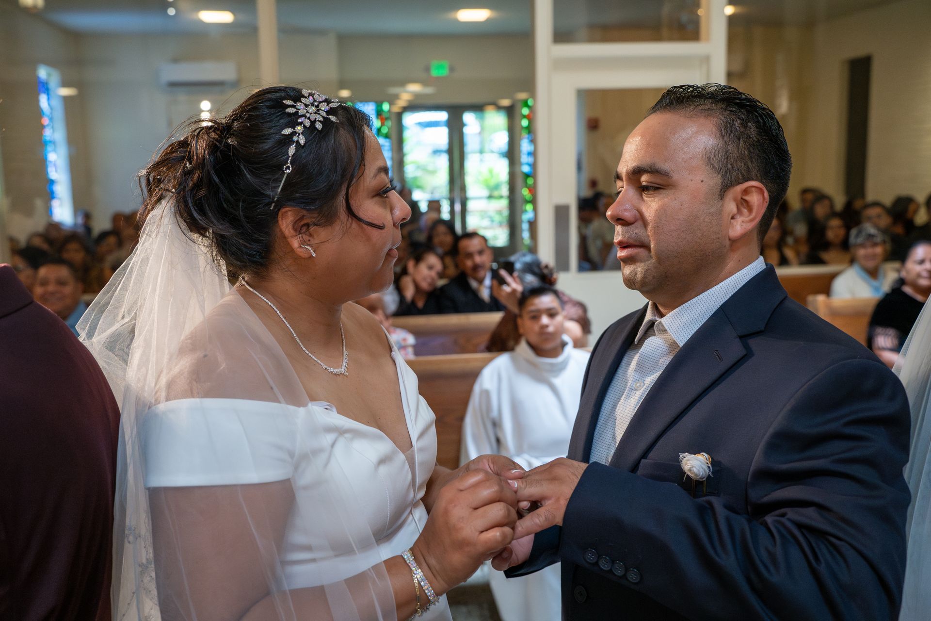 Bride and groom exchanging rings during a wedding ceremony in a church.