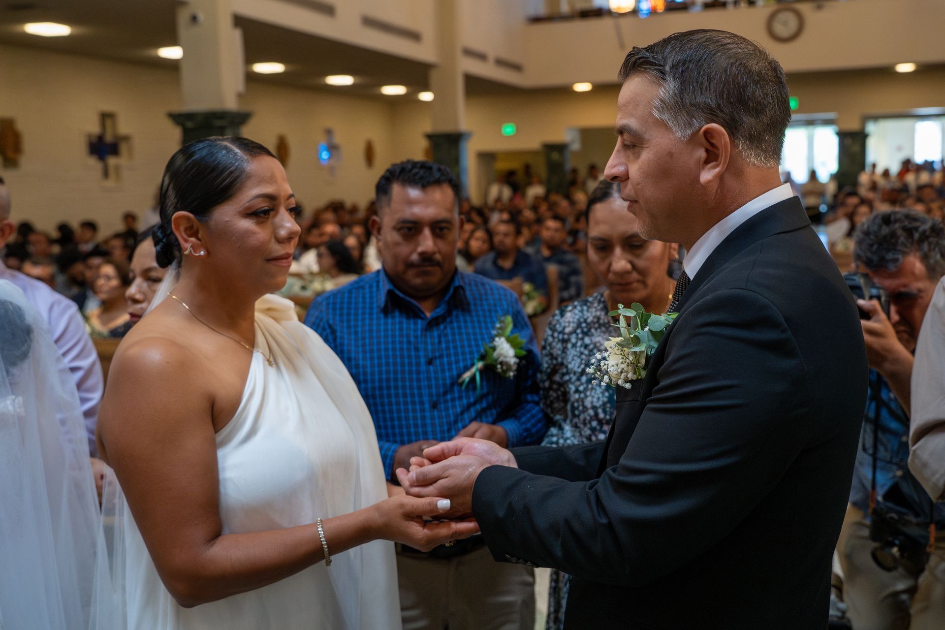 Couple exchanging rings during a wedding ceremony in a crowded hall