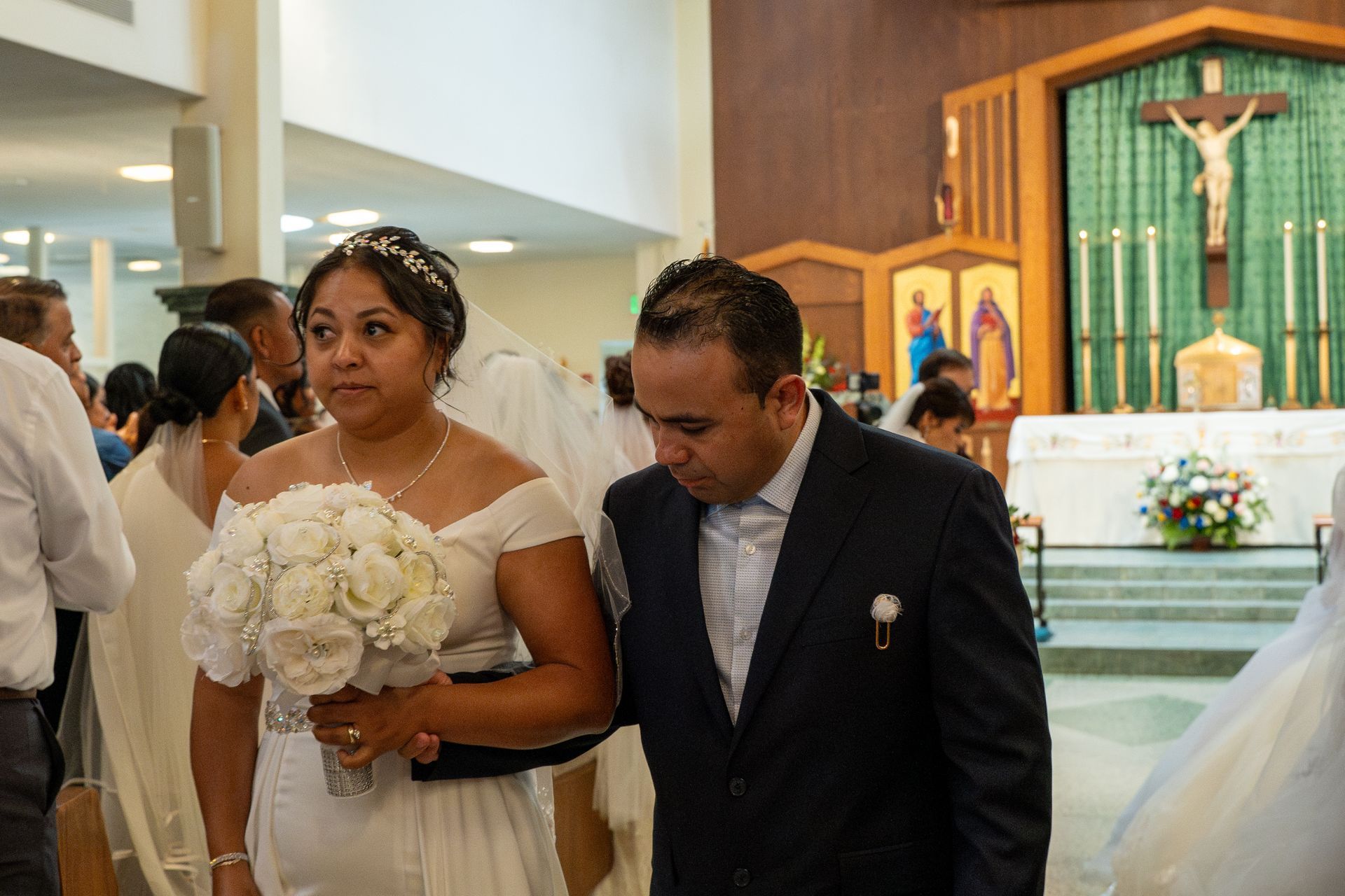 Bride holding white bouquet beside groom in dark suit during church wedding ceremony